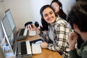 girl smiling at a desk, holding headphones